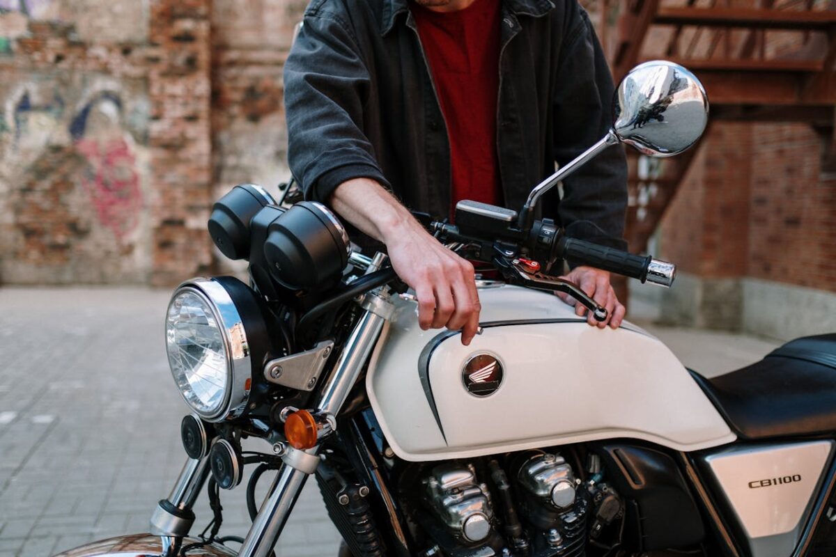 Technician working on a motorcycle outdoors, focusing on maintenance and adjustments.