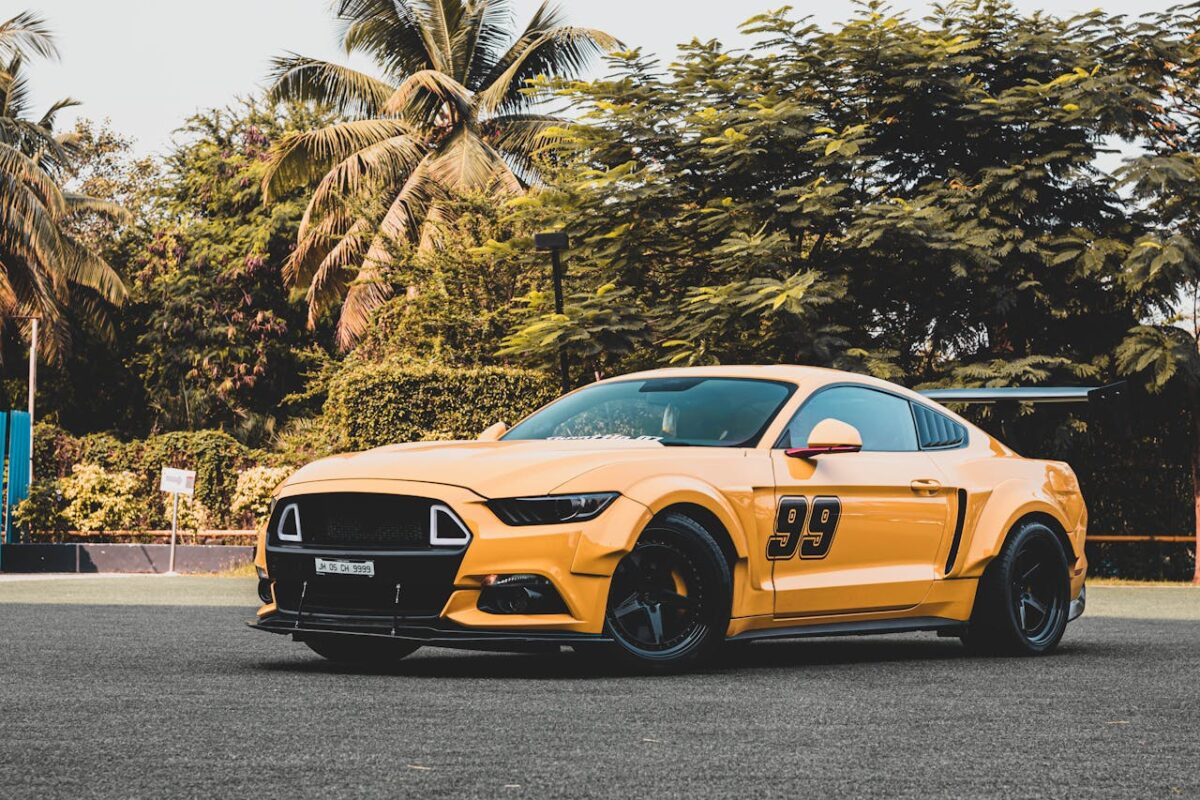 A sleek yellow sports car with the number 99 parked outdoors among lush palm trees, capturing a tropical vibe.